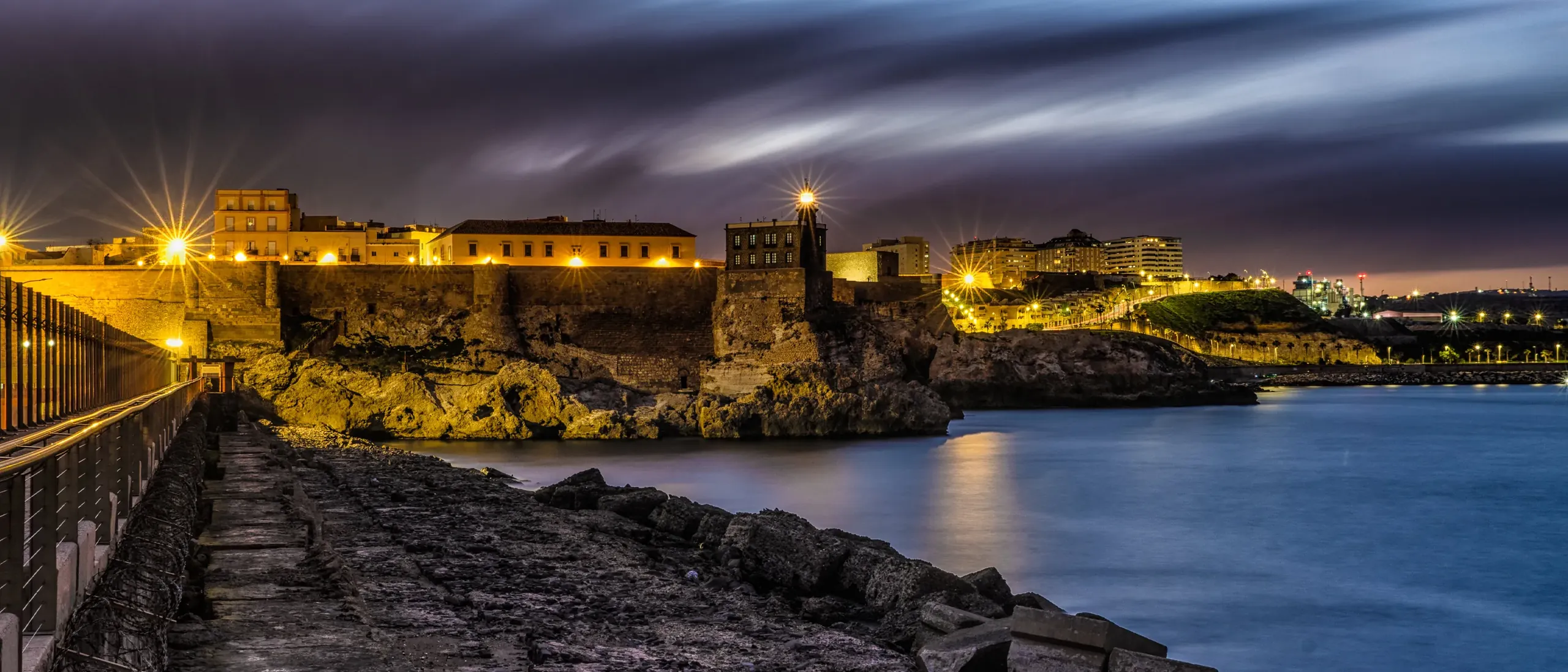 Melilla la Vieja de noche, con el faro y las murallas iluminadas junto al mar
